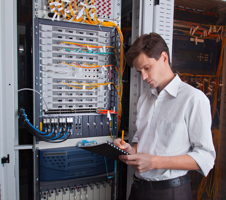 Network engineer in server room with pen and tablet
